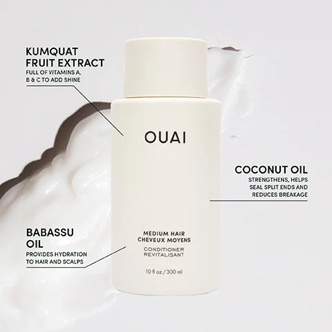 A bottle of OUAI conditioner for medium hair is shown, with the text indicating key ingredients: Kumquat Fruit Extract, Coconut Oil, and Babassu Oil, alongside their benefits for hair; the bottle is surrounded by a creamy white substance.